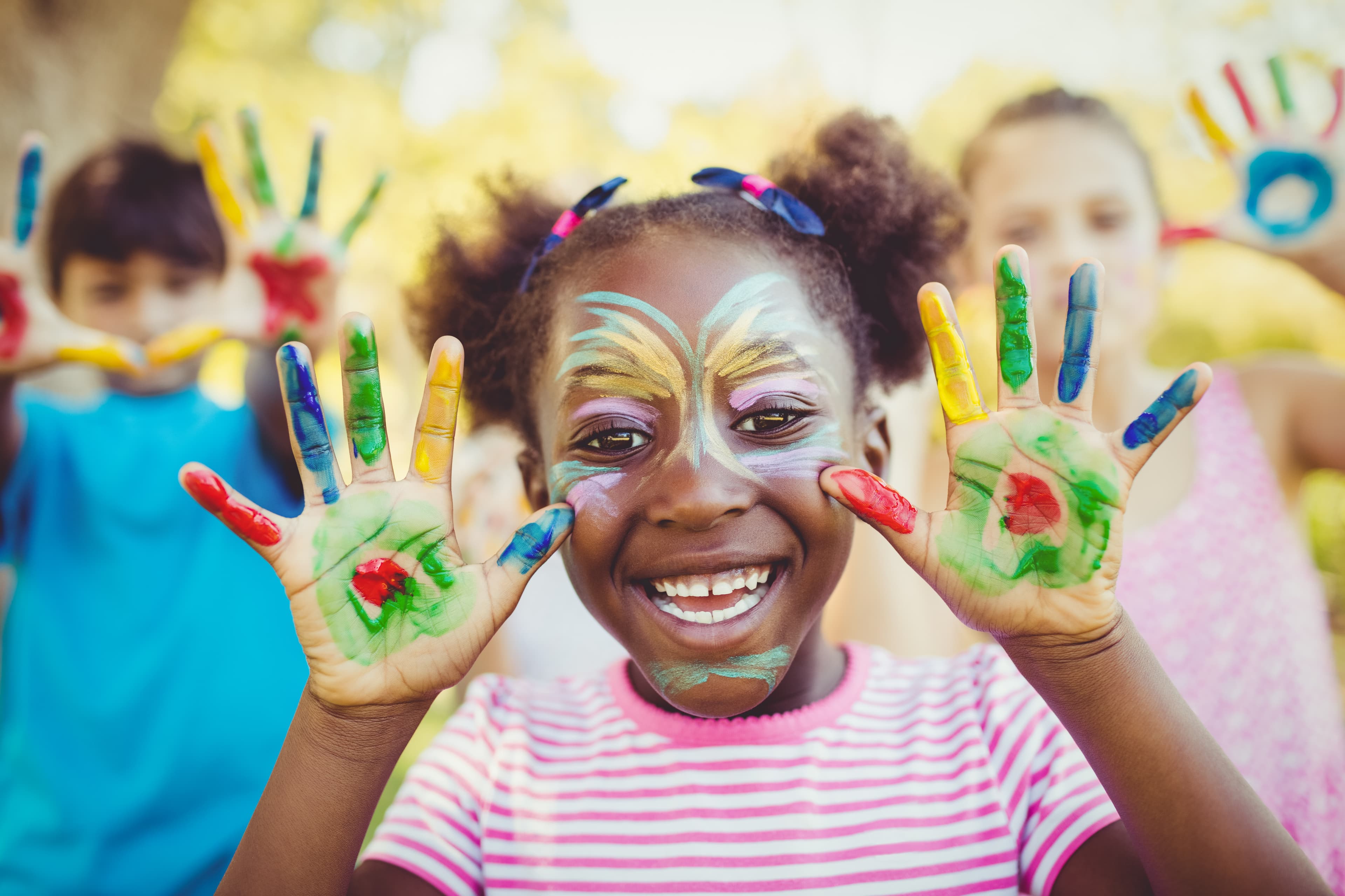 Portrait of a girl with make-up showing her painted hands in a park